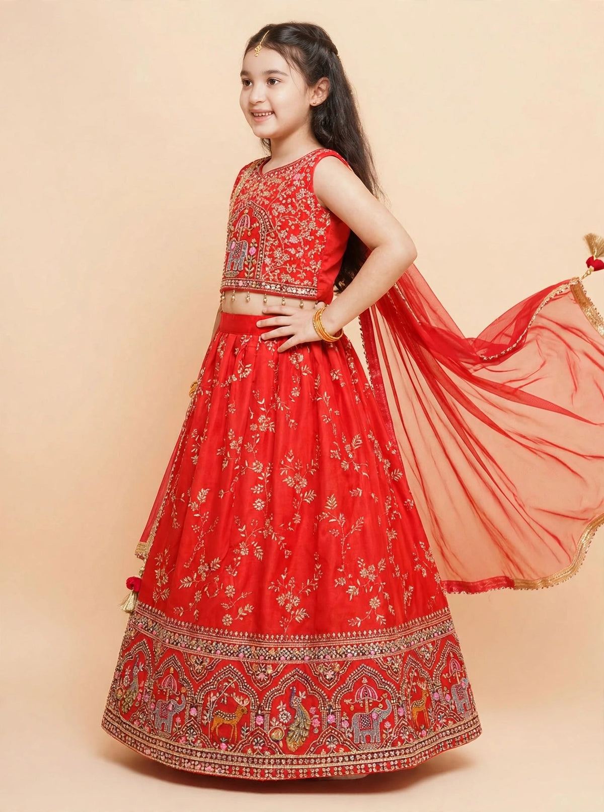 Full-length girls red lehenga choli with elephant motifs and tasselled dupatta
