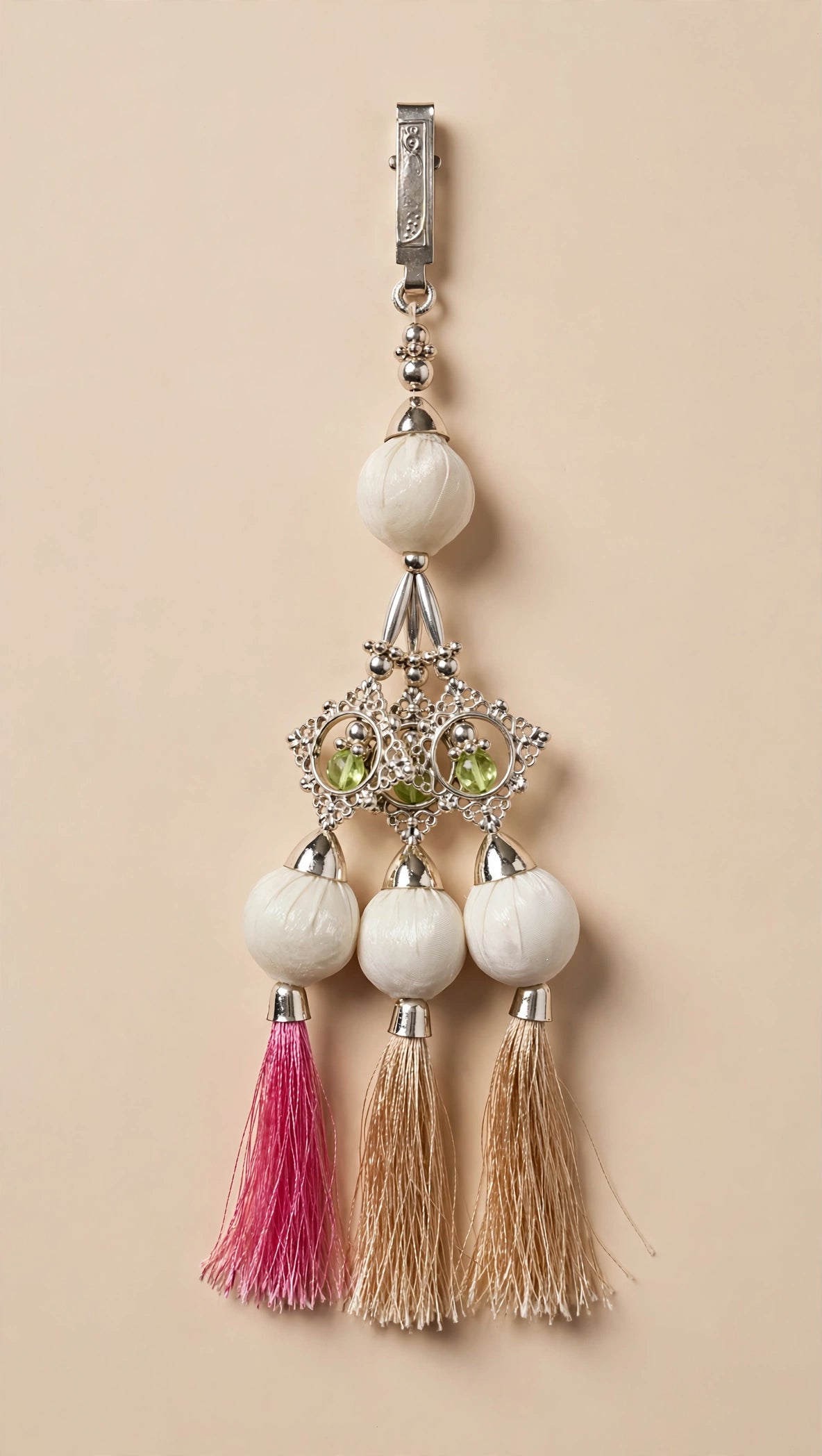 Close-up of lehenga latkan with white potli balls, filigree pendant and pink-beige tassels