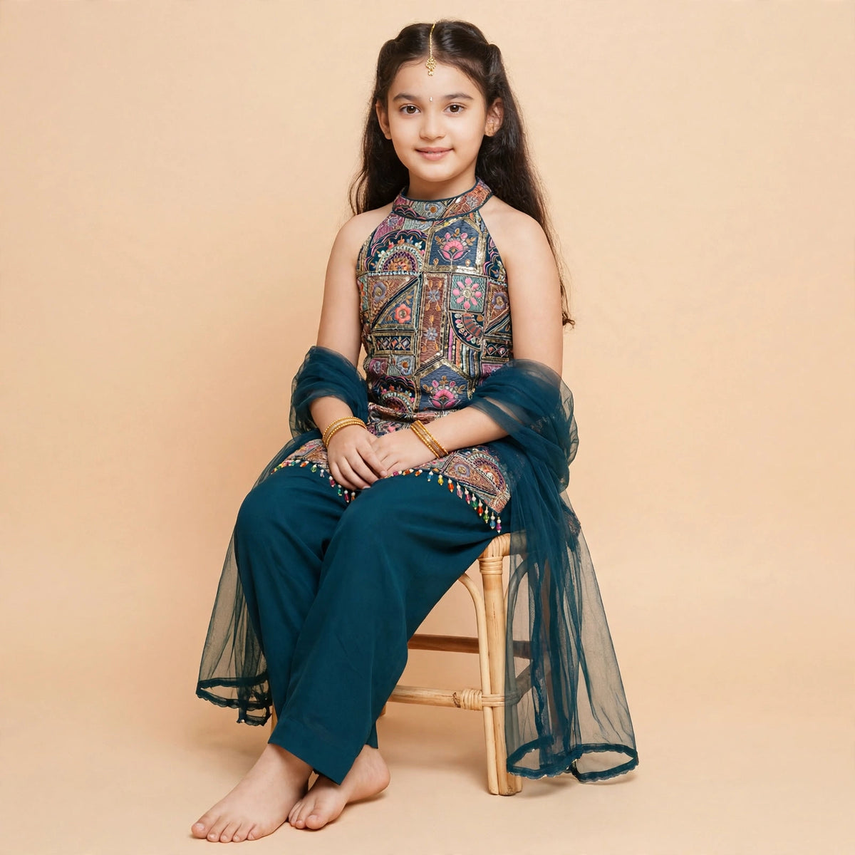 Seated view of girls teal patchwork embroidered halter choli with plain pajama and sheer dupatta