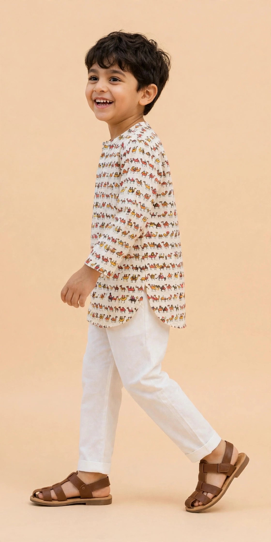 Boy seated on a stool wearing cream camel print kurta and white pajama