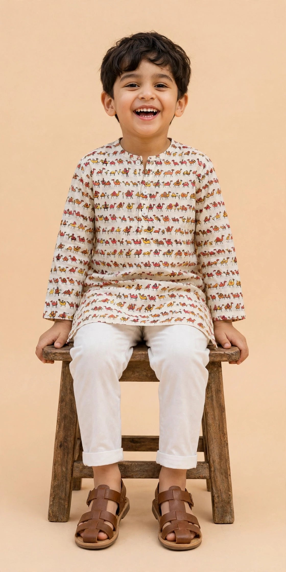 Boy wearing cream camel print kurta and white pajama pants, front view