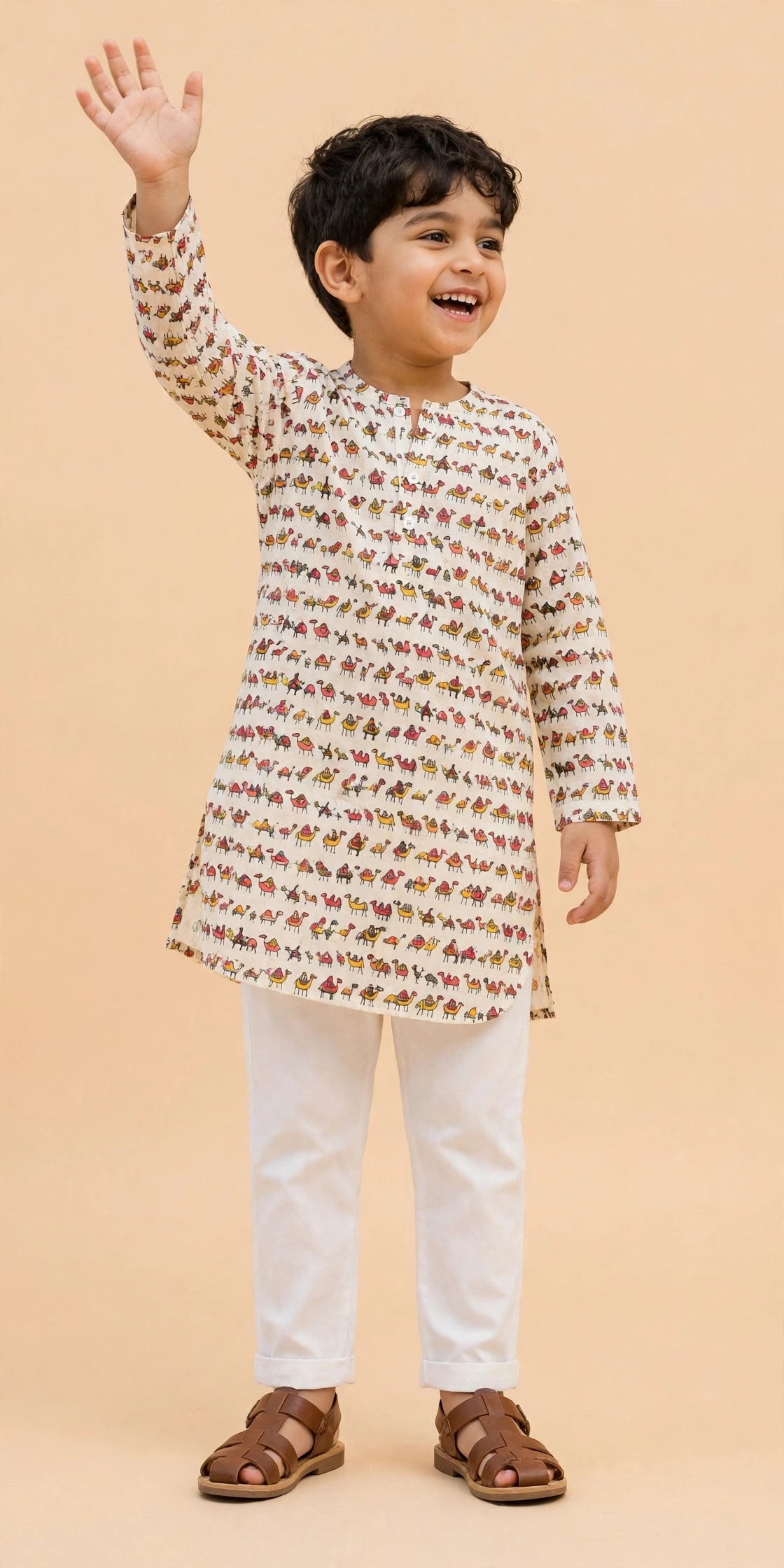 Boy sitting cross-legged in cream camel print kurta pajama set