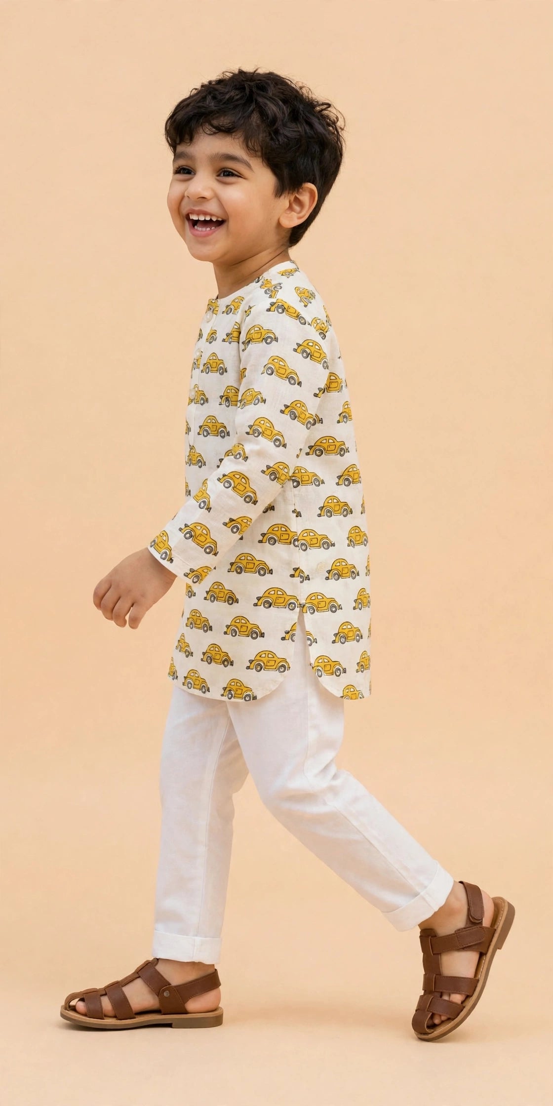 Boy waving in cream yellow car print kurta pajama set