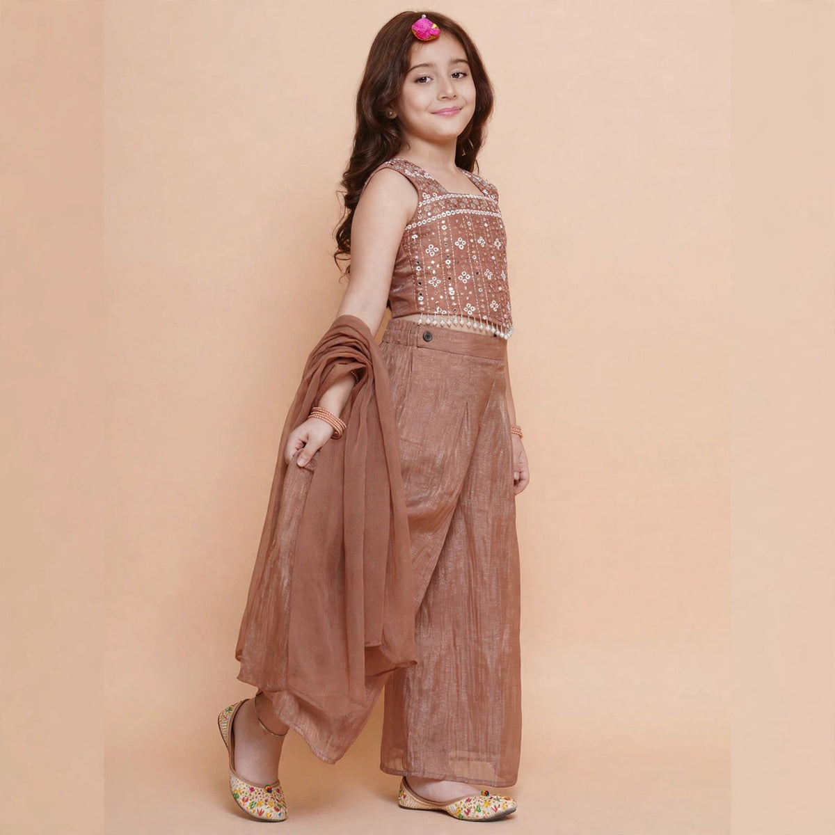 Angled view of girls copper brown sleeveless choli, pleated palazzo pants and sheer dupatta