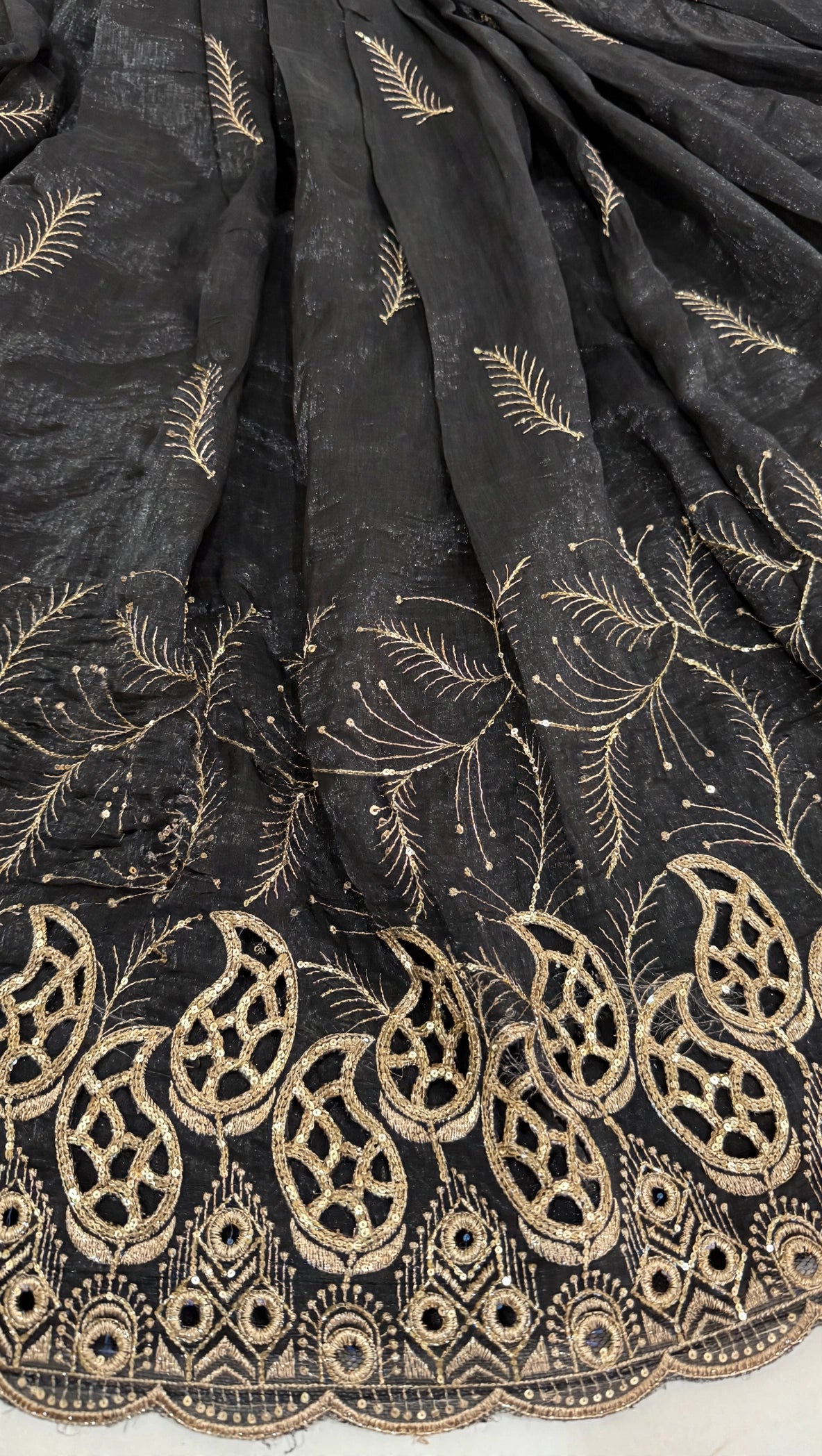 Close-up of gold feather embroidery and cutwork paisley border on black lehenga