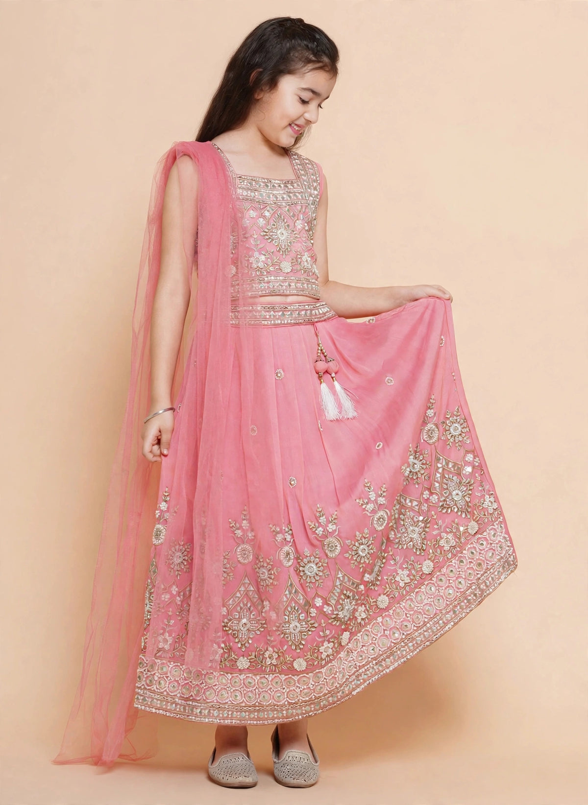 Girls twirling in pink lehenga showing wide ornate gold embroidered border