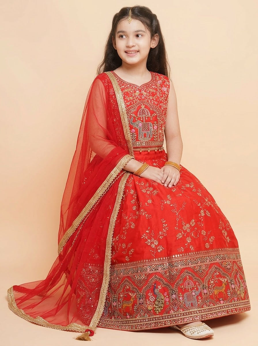 Seated view of girls red festive lehenga showing patterned skirt border