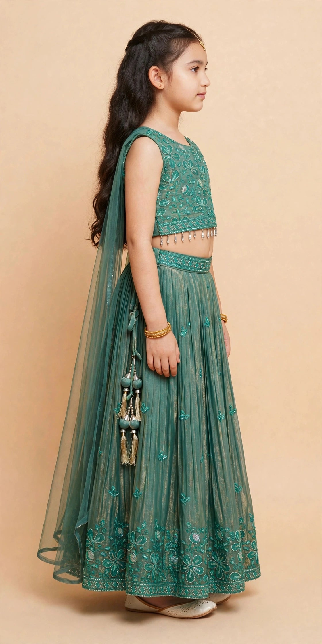 Side view of girls deep green embroidered lehenga choli with crystal-drop hem fringe and tassel latkan